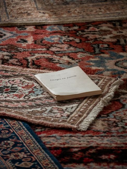 Close-up of a beige carpet with an intricate pattern of dark brown lines and swirls, showing a textured surface with visible fibers. The carpet appears clean and well-maintained, situated in a room wi